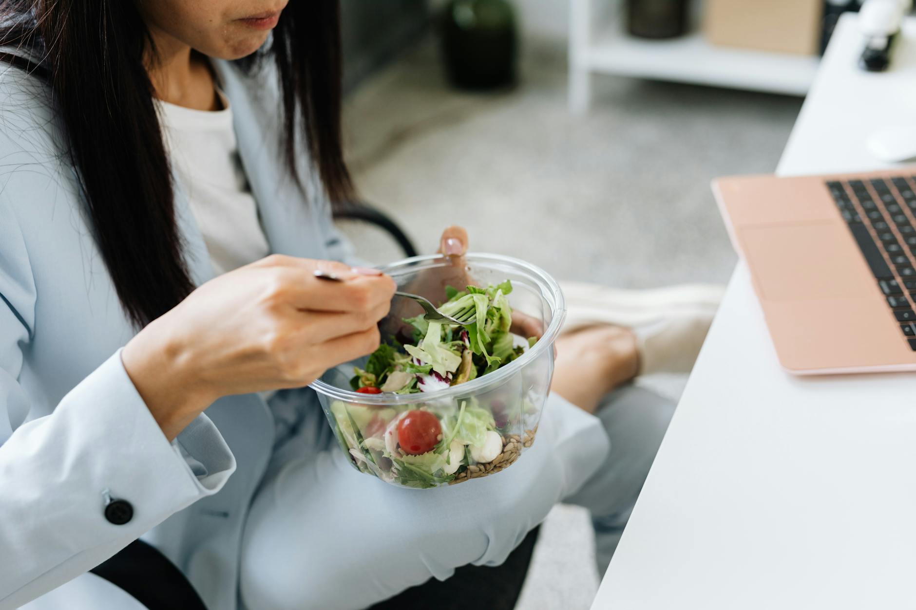 person wearing blazer eating vegetable salad